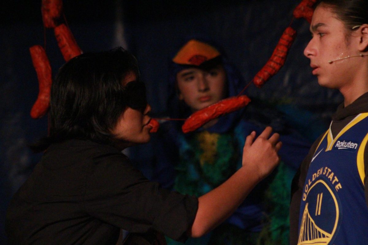 Jubilee Kaleikau as Mr. Zyclo (left) and Colby Tong as Anon (right) have a dialogue in the butcher shop, in Anon(ymous) production on Nov. 21, 2025.