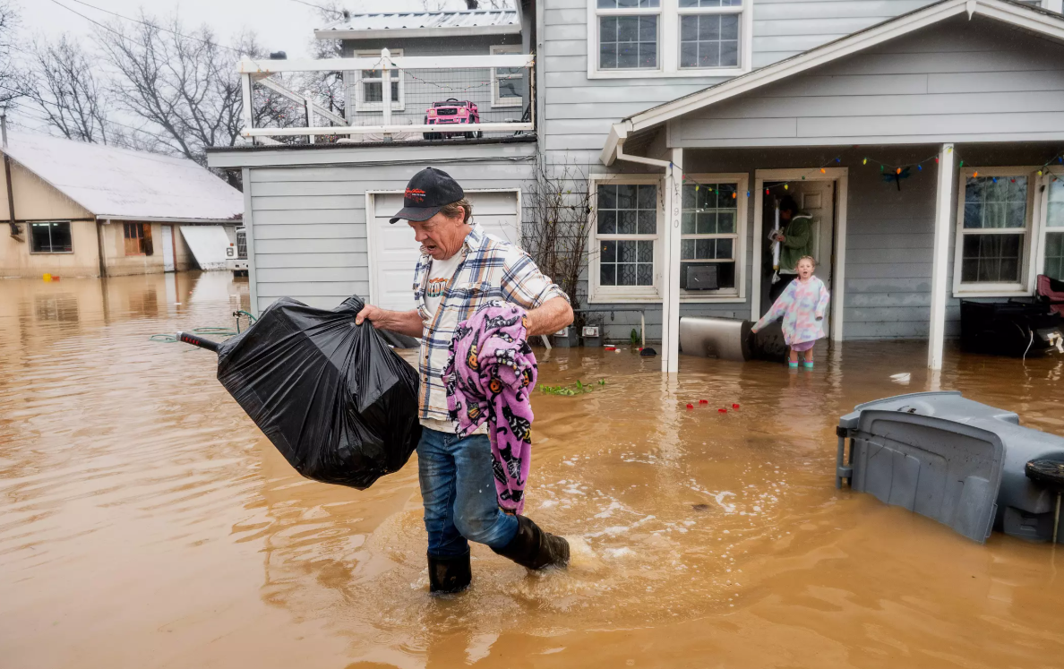 CA resident carries Christmas presents from his granddaughter’s flooded home in Redding, CA. (Noah Berger / Associated Press)
