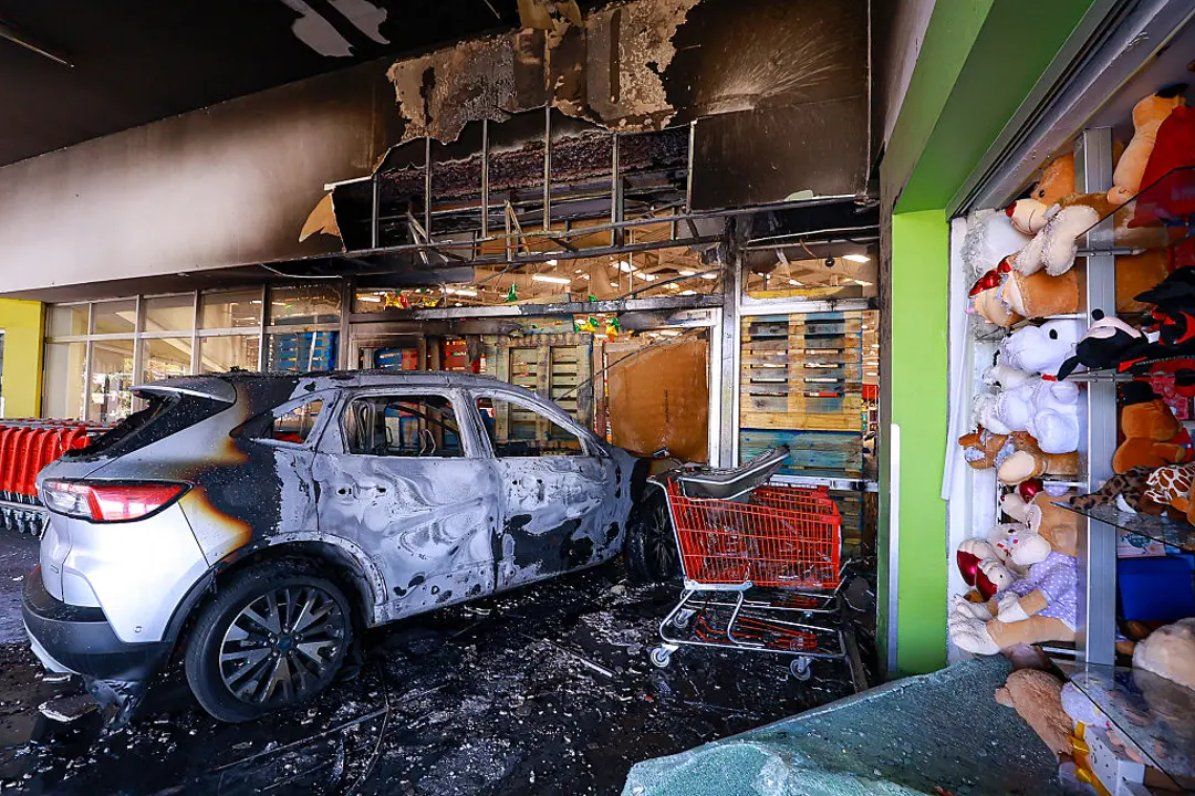 Carlos Zapeda _ Getty Images - A burnt car crashes through a storefront in Guadalajara, Mexico, on Feb. 22, 2026.